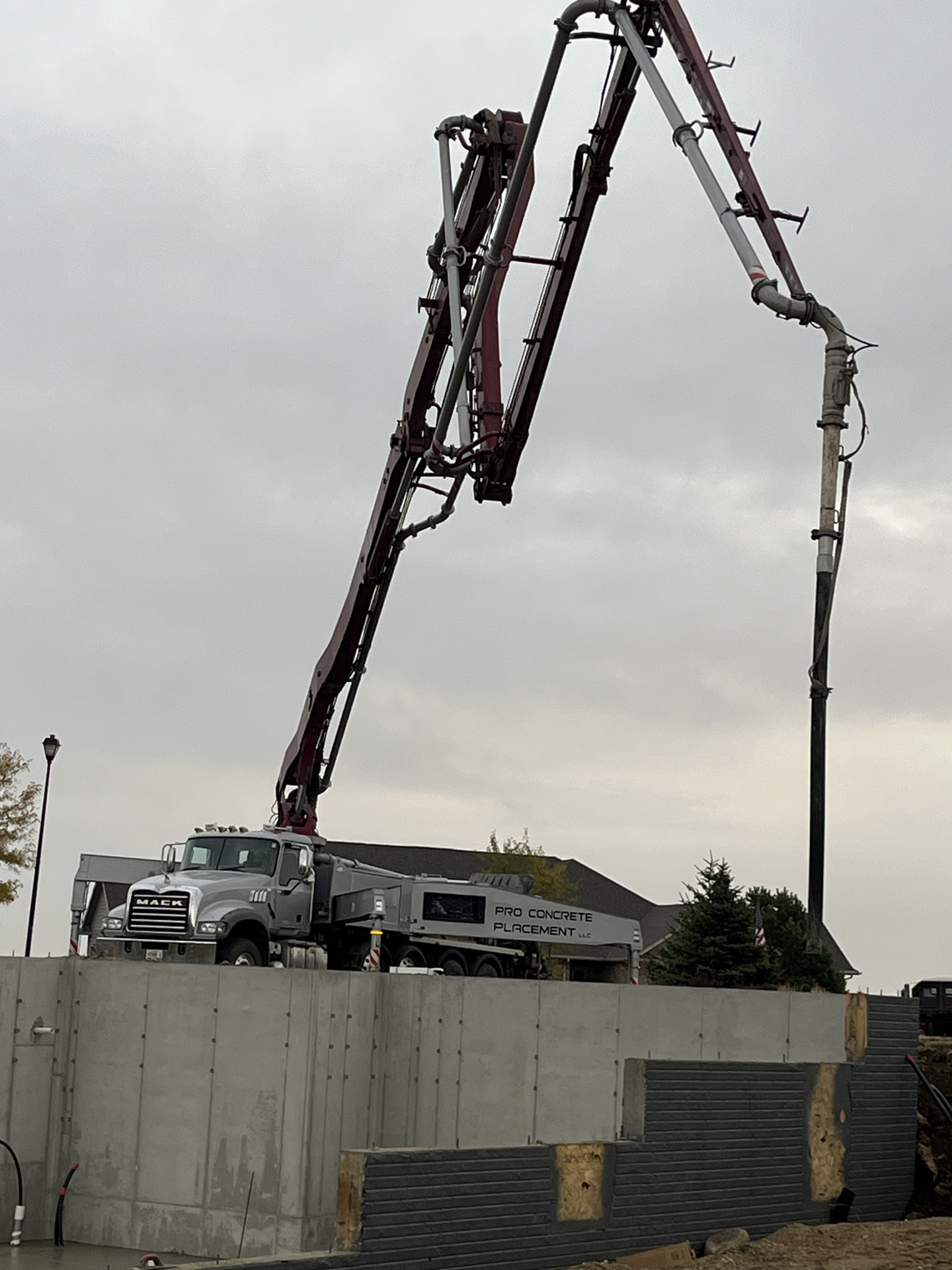 Boom pump placing concrete into foundation wall forms