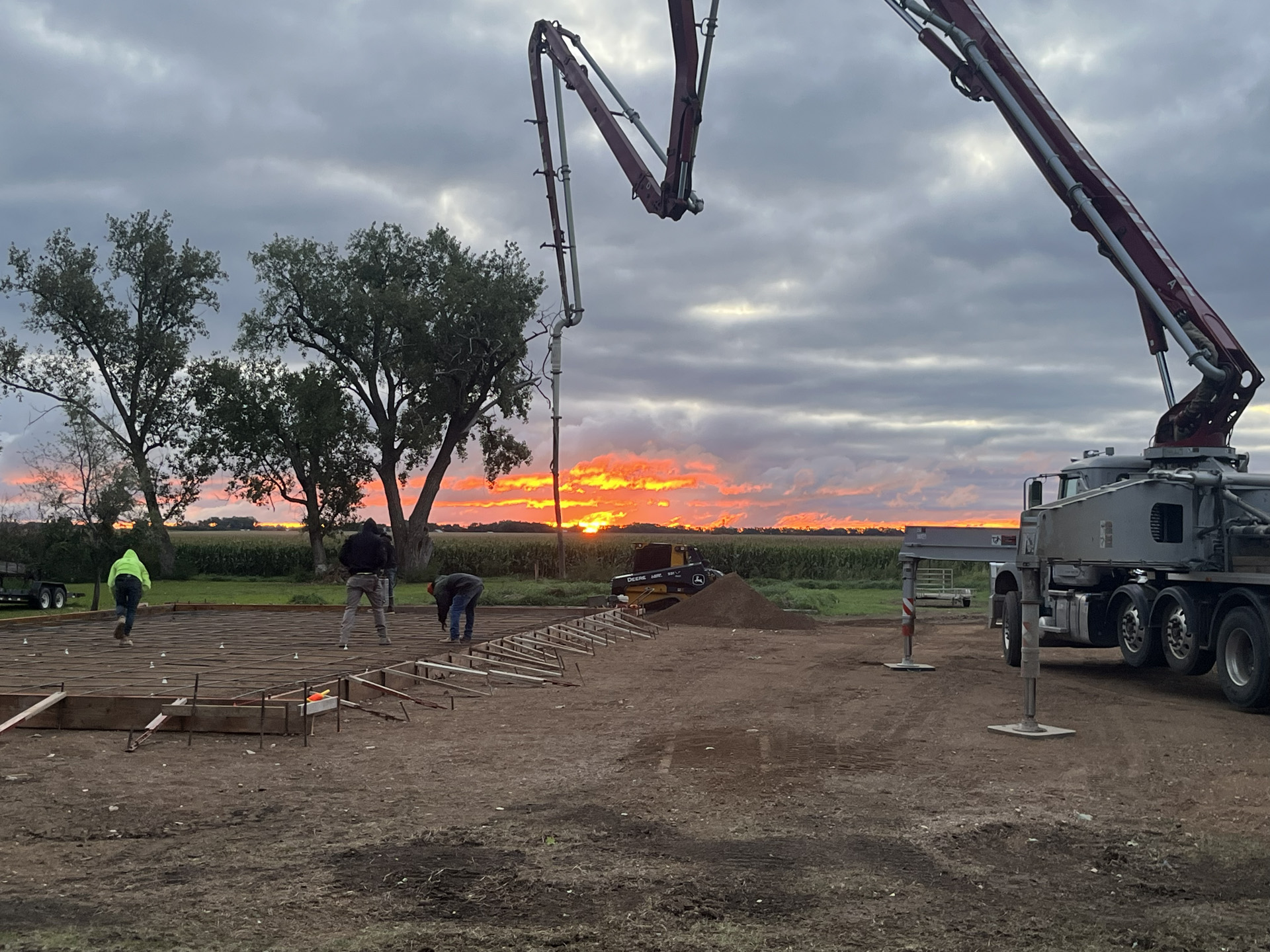 Concrete boom pump at a foundation site near sunrise